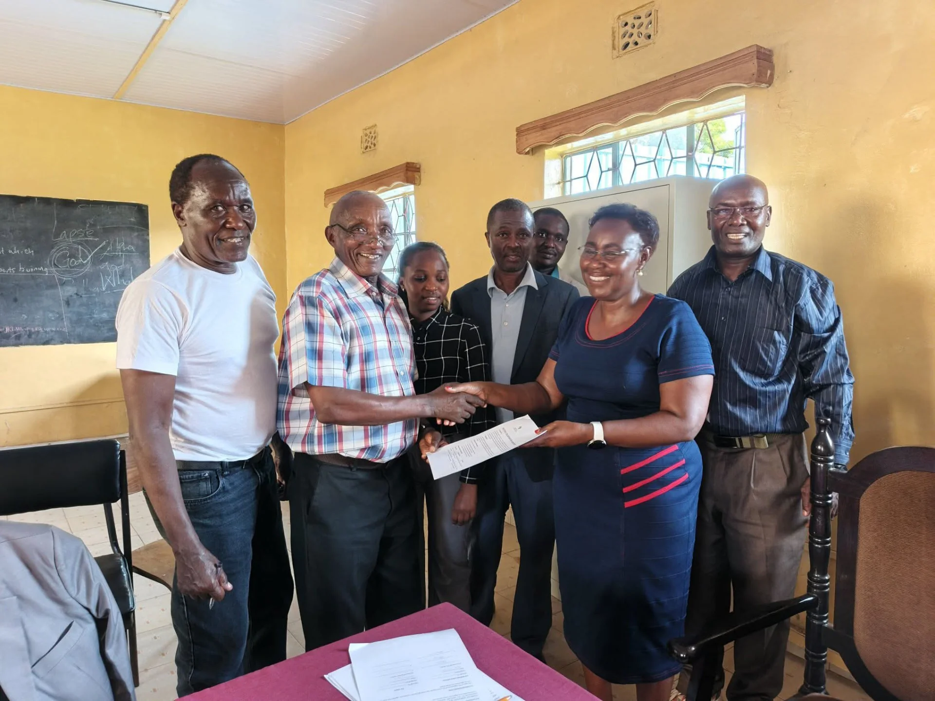 A handshake and document handover mark a moment of collaboration.