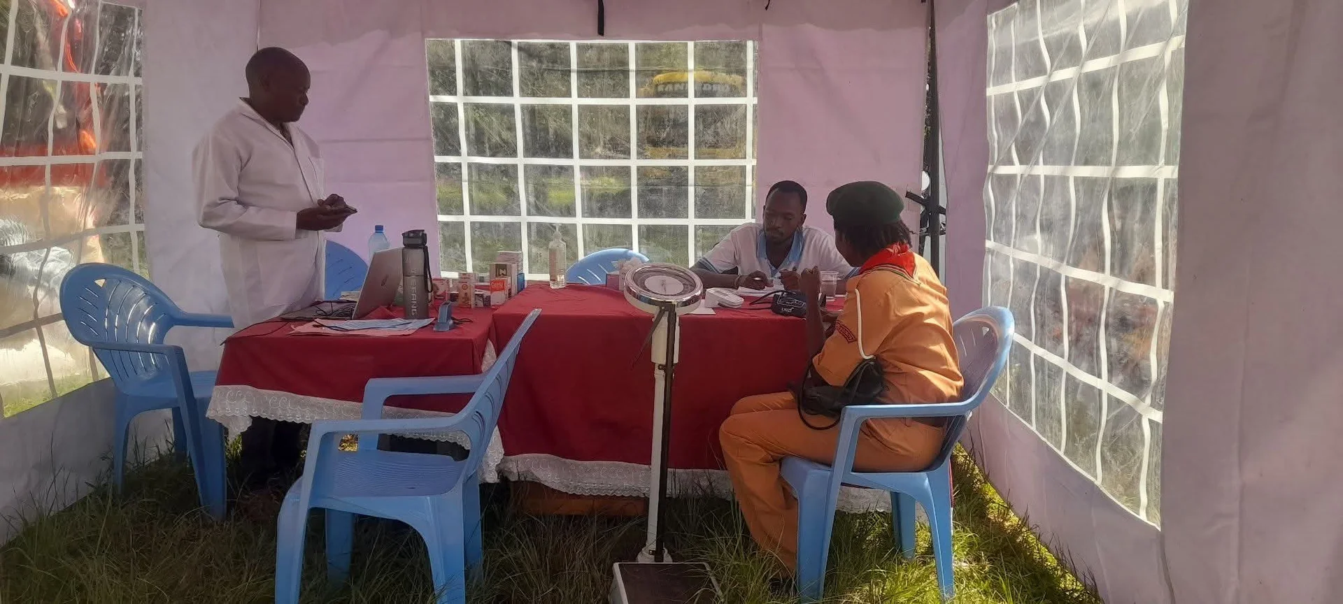 Healthcare professionals meet with a visitor at an outdoor consultation station.